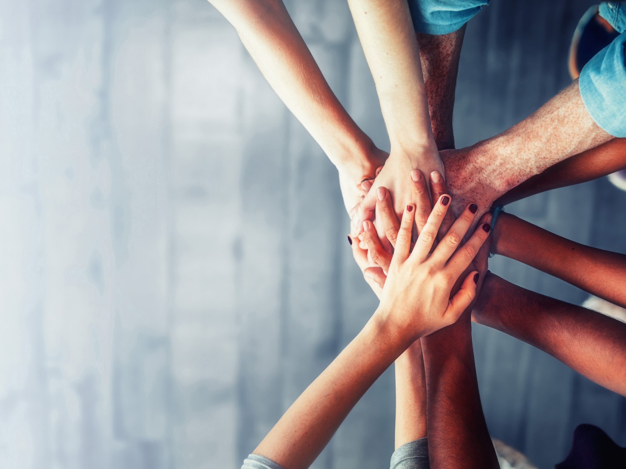 Close up top view of young business people putting their hands t